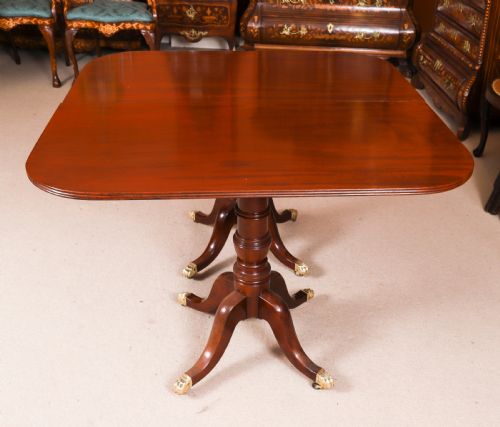 fig 4. A George III Regency period mahogany twin pillar dining table featuring reeded edge detail and tripod pedestal legs with brass castors.