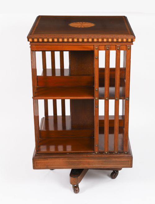 fig 1. An Edwardian flame mahogany revolving bookcase featuring two tiers, vertical slatted sides with brass studs, satinwood inlay, and castors.