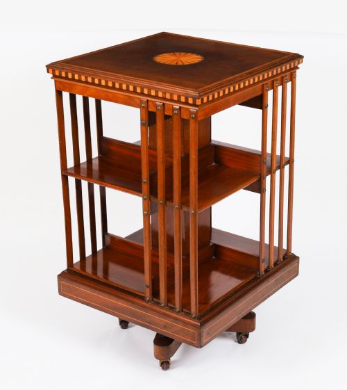fig 2. An Edwardian flame mahogany revolving bookcase featuring two tiers, vertical slatted sides with brass studs, satinwood inlay, and castors.