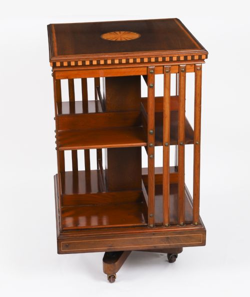 fig 4. An Edwardian flame mahogany revolving bookcase featuring two tiers, vertical slatted sides with brass studs, satinwood inlay, and castors.