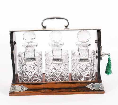 fig 1. An Edwardian Betjemanns coromandel wood tantalus with hallmarked silver mounts holding three cut-crystal decanters.