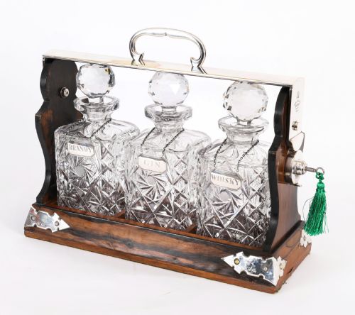 fig 3. An Edwardian Betjemanns coromandel wood tantalus with hallmarked silver mounts holding three cut-crystal decanters.