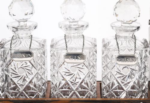 fig 4. An Edwardian Betjemanns coromandel wood tantalus with hallmarked silver mounts holding three cut-crystal decanters.