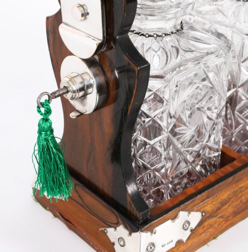 fig 8. An Edwardian Betjemanns coromandel wood tantalus with hallmarked silver mounts holding three cut-crystal decanters.