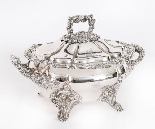 fig 1. A pair of silver-plated oval sauce tureens featuring domed lids, foliate scroll handles, and decorative carved feet.