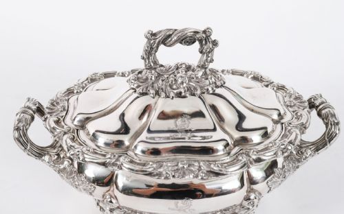 fig 3. A pair of silver-plated oval sauce tureens featuring domed lids, foliate scroll handles, and decorative carved feet.