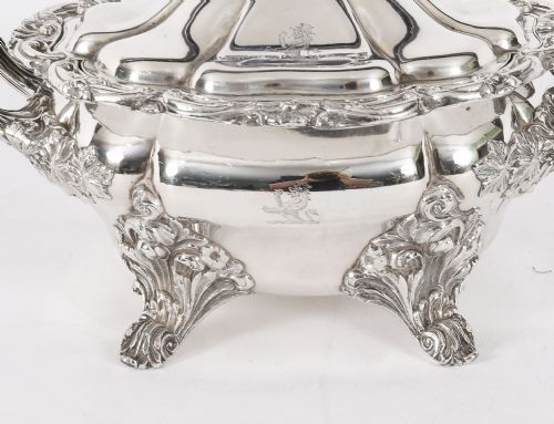 fig 4. A pair of silver-plated oval sauce tureens featuring domed lids, foliate scroll handles, and decorative carved feet.
