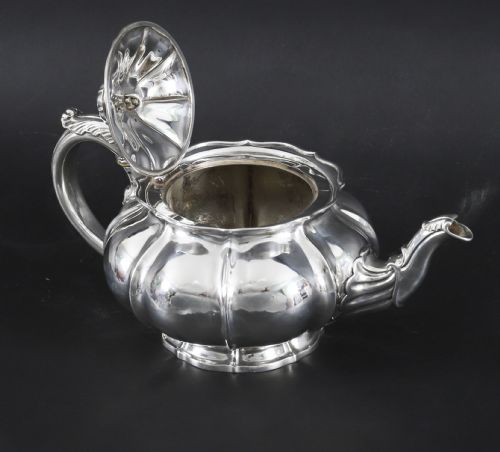 fig 1. A Georgian sterling silver teapot featuring a lobed melon-shaped body, leaf-engraved spout, and insulated handle.