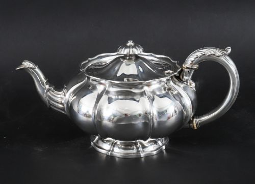 fig 3. A Georgian sterling silver teapot featuring a lobed melon-shaped body, leaf-engraved spout, and insulated handle.
