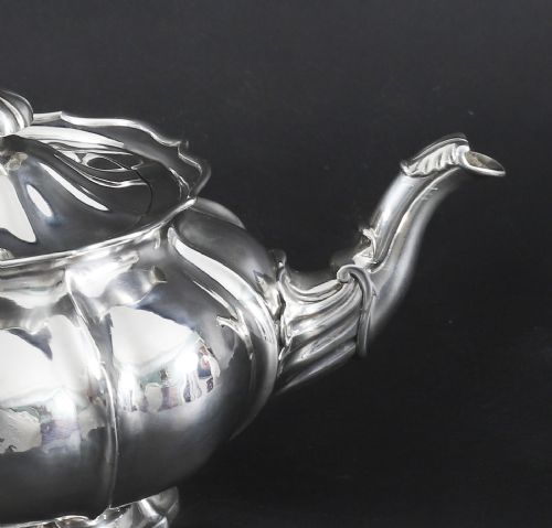 fig 4. A Georgian sterling silver teapot featuring a lobed melon-shaped body, leaf-engraved spout, and insulated handle.