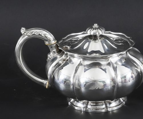 fig 5. A Georgian sterling silver teapot featuring a lobed melon-shaped body, leaf-engraved spout, and insulated handle.