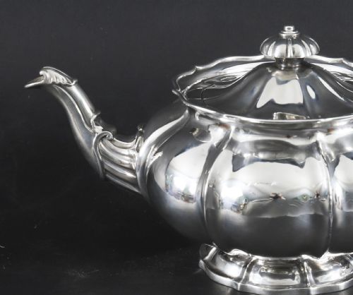 fig 6. A Georgian sterling silver teapot featuring a lobed melon-shaped body, leaf-engraved spout, and insulated handle.