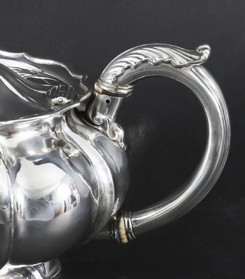 fig 7. A Georgian sterling silver teapot featuring a lobed melon-shaped body, leaf-engraved spout, and insulated handle.