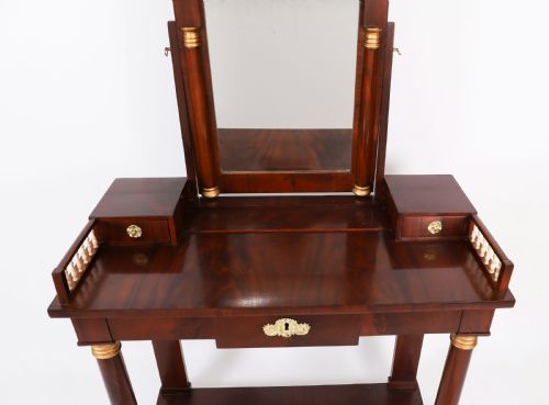 fig 1. A 19th-century French Empire mahogany dressing table with a central adjustable mirror, gilded column supports, small side drawers, and a lower curved stretcher.