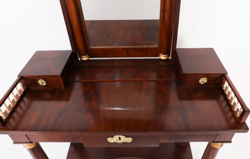 fig 2. A 19th-century French Empire mahogany dressing table with a central adjustable mirror, gilded column supports, small side drawers, and a lower curved stretcher.
