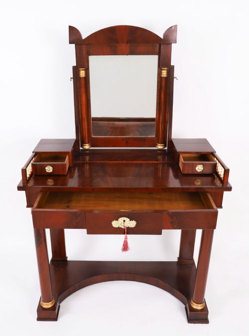 fig 6. A 19th-century French Empire mahogany dressing table with a central adjustable mirror, gilded column supports, small side drawers, and a lower curved stretcher.