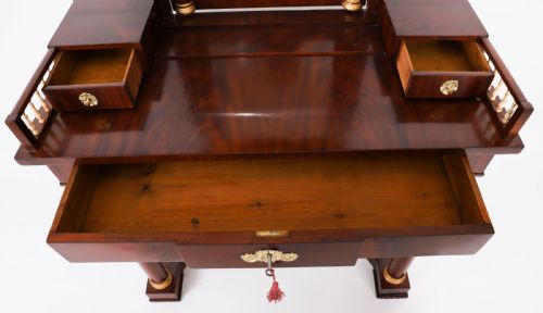 fig 7. A 19th-century French Empire mahogany dressing table with a central adjustable mirror, gilded column supports, small side drawers, and a lower curved stretcher.