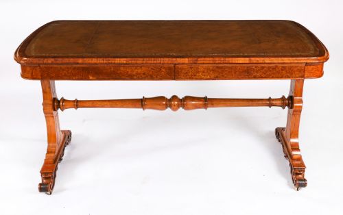 fig 1. A 19th-century Victorian pollard oak writing table featuring a brown leather inset top, carved trestle end supports, a turned central stretcher, and scroll feet on brass castors.