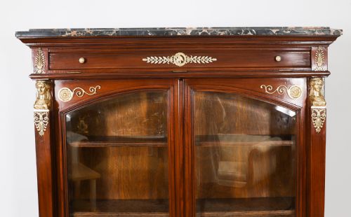 fig 3. A nineteenth-century French Empire Revival mahogany bookcase featuring twin glazed doors, gilt bronze mounts, a marble top, and metal paw feet.
