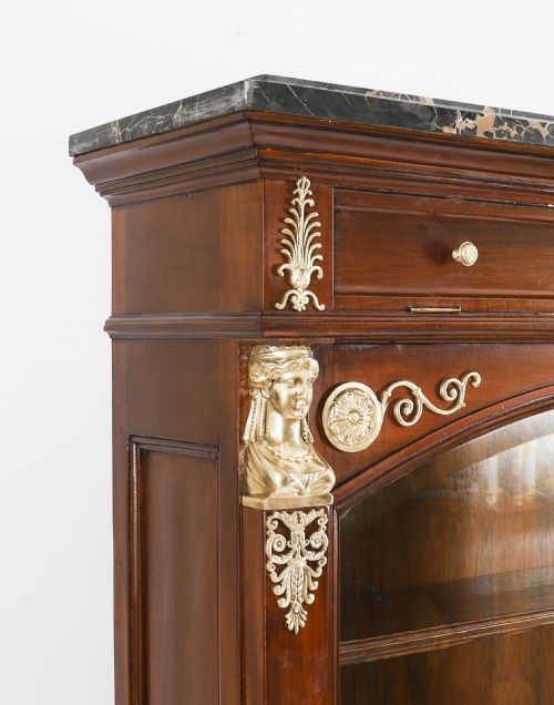 fig 4. A nineteenth-century French Empire Revival mahogany bookcase featuring twin glazed doors, gilt bronze mounts, a marble top, and metal paw feet.