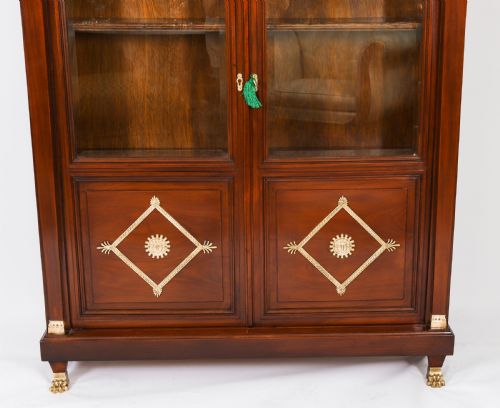fig 5. A nineteenth-century French Empire Revival mahogany bookcase featuring twin glazed doors, gilt bronze mounts, a marble top, and metal paw feet.