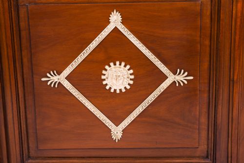 fig 7. A nineteenth-century French Empire Revival mahogany bookcase featuring twin glazed doors, gilt bronze mounts, a marble top, and metal paw feet.