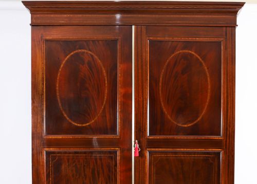fig 2. A late 19th-century George III revival flame mahogany double wardrobe featuring oval panel inlays, twin doors, a single bottom drawer, and a moulded cornice.