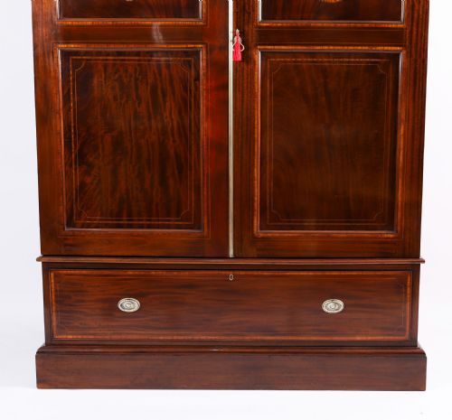 fig 3. A late 19th-century George III revival flame mahogany double wardrobe featuring oval panel inlays, twin doors, a single bottom drawer, and a moulded cornice.