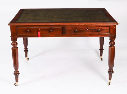 fig 1. A nineteenth-century Victorian mahogany partners writing desk featuring a green leather inset top, frieze drawers with turned wood knob handles, and tapered legs on brass castors.