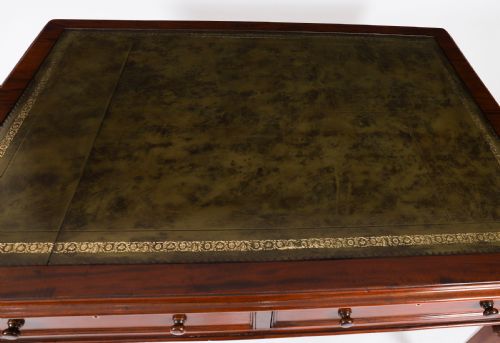 fig 3. A nineteenth-century Victorian mahogany partners writing desk featuring a green leather inset top, frieze drawers with turned wood knob handles, and tapered legs on brass castors.