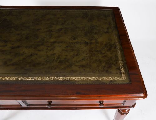 fig 4. A nineteenth-century Victorian mahogany partners writing desk featuring a green leather inset top, frieze drawers with turned wood knob handles, and tapered legs on brass castors.