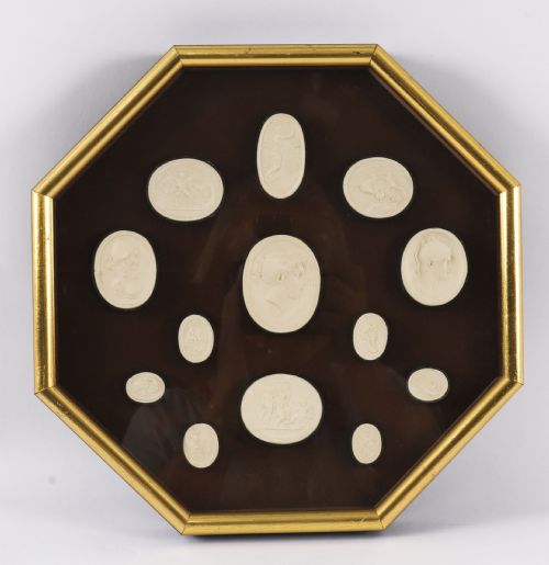 fig 1. A pair of octagonal giltwood framed wall displays featuring multiple cream plaster intaglio impressions mounted against a dark brown background.
