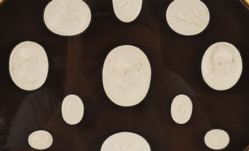 fig 4. A pair of octagonal giltwood framed wall displays featuring multiple cream plaster intaglio impressions mounted against a dark brown background.