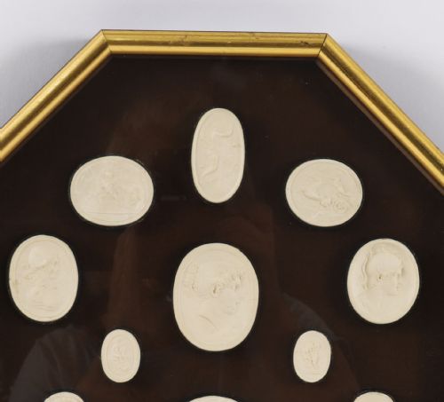 fig 5. A pair of octagonal giltwood framed wall displays featuring multiple cream plaster intaglio impressions mounted against a dark brown background.