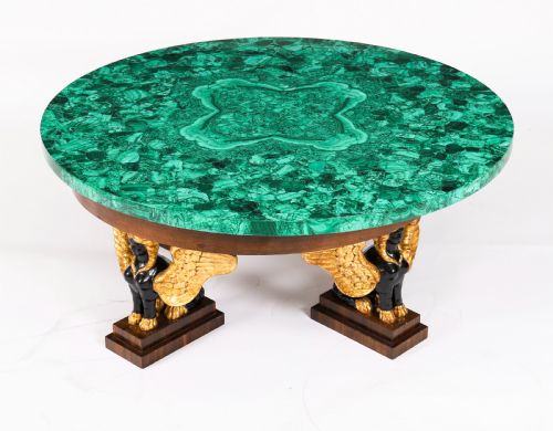 fig 2. A round coffee table featuring a green malachite stone veneer top supported by three carved ebonised and giltwood winged sphinx legs on dark plinth bases.