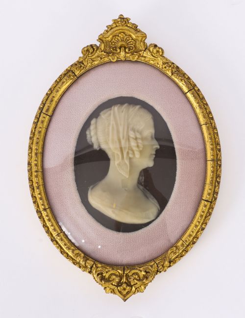 fig 2. A pair of oval gilt-framed 19th-century wax portrait reliefs featuring male and female profile busts set against dark backgrounds with pink fabric mounts.