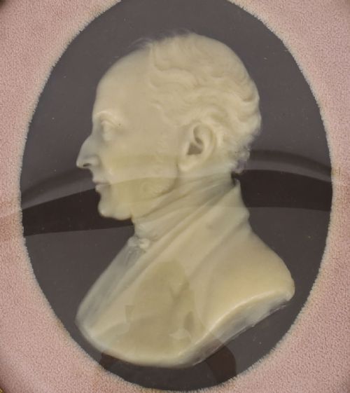 fig 4. A pair of oval gilt-framed 19th-century wax portrait reliefs featuring male and female profile busts set against dark backgrounds with pink fabric mounts.