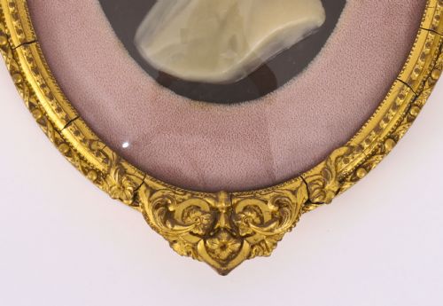 fig 5. A pair of oval gilt-framed 19th-century wax portrait reliefs featuring male and female profile busts set against dark backgrounds with pink fabric mounts.