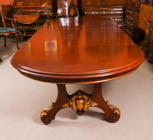 fig 4. A large, polished mahogany extending dining table supported by two carved twin pedestals with parcel-gilt detailing.