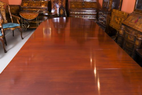 fig 7. A large, polished mahogany extending dining table supported by two carved twin pedestals with parcel-gilt detailing.