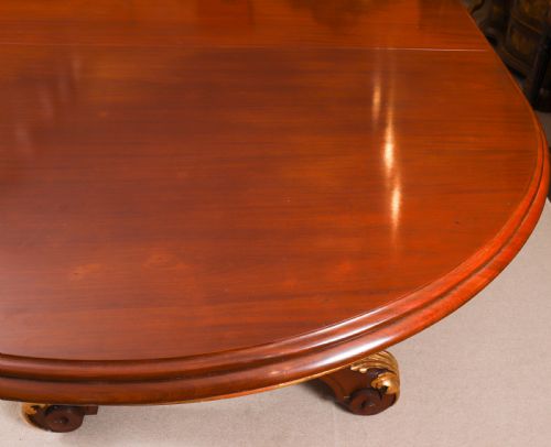 fig 8. A large, polished mahogany extending dining table supported by two carved twin pedestals with parcel-gilt detailing.