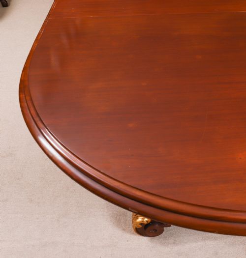 fig 9. A large, polished mahogany extending dining table supported by two carved twin pedestals with parcel-gilt detailing.