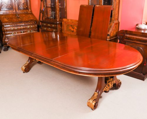 fig 10. A large, polished mahogany extending dining table supported by two carved twin pedestals with parcel-gilt detailing.
