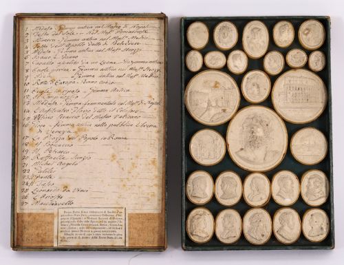 fig 1. An 18th-century boxed set of cream plaster Grand Tour intaglios showing classical profile portraits and Roman architectural scenes alongside an Italian manuscript index.