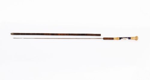 fig 3. A 19th-century French sword stick featuring a chased gold-plated pommel and a hand-painted Sevres style cobalt blue porcelain collar above a wooden shaft with a partially drawn steel blade.