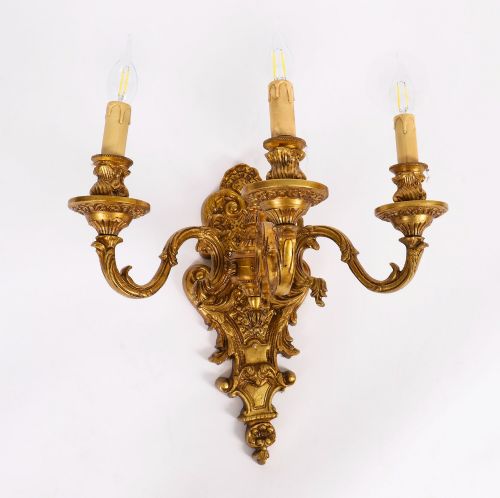 fig 2. A set of four French Rococo style gilt bronze wall lights, each featuring three scrolling arms adorned with acanthus leaf motifs and candle drip sockets.