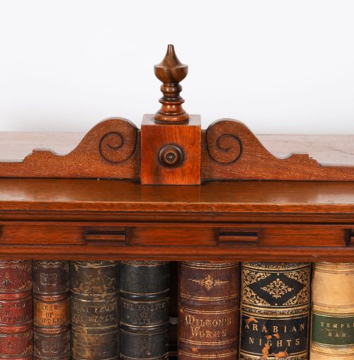 fig 2. An antique Victorian walnut tabletop collectors cabinet featuring a front styled with vintage book spines, turned columns, turned feet, and a central finial top.