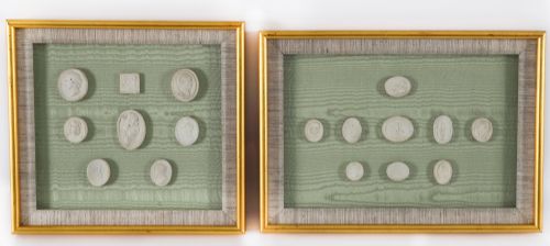 fig 1. A pair of framed displays containing white plaster intaglio relief medallions mounted on green patterned fabric inside gilt frames.