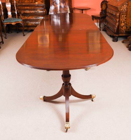 fig 1. An extended mahogany Regency Revival triple pillar dining table with reeded legs and brass paw castors.
