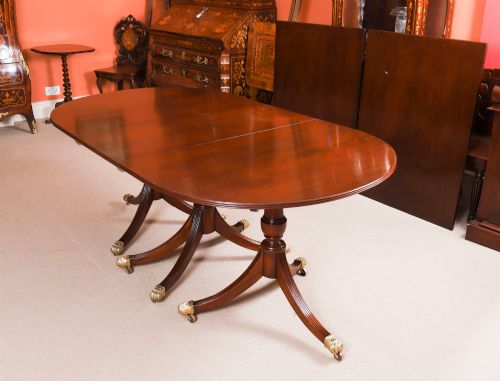 fig 4. An extended mahogany Regency Revival triple pillar dining table with reeded legs and brass paw castors.